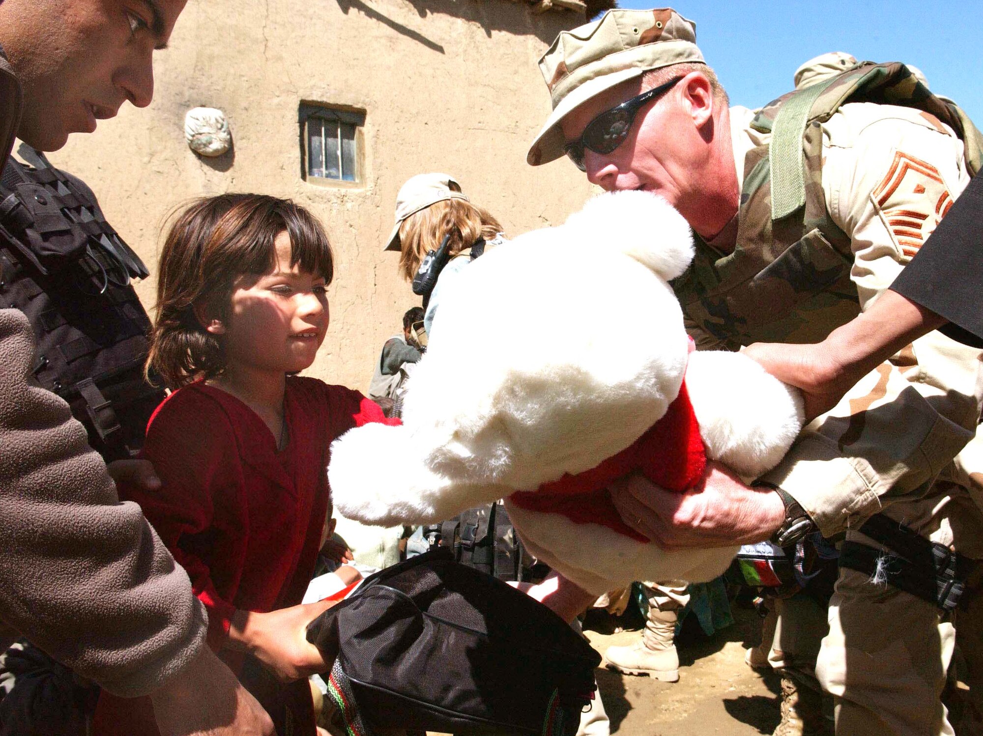 JA FARKEL, Afghanistan - Senior Master Sgt. Tim Bolon gives a teddy bear and a bag of school supplies to an Afghan girl during an Adopt-A-Village visit.  He is the 455th Expeditionary Mission Support Group first sergeant at nearby Bagram Air Base.  (U.S. Air Force photo by Capt. Catie Hague)