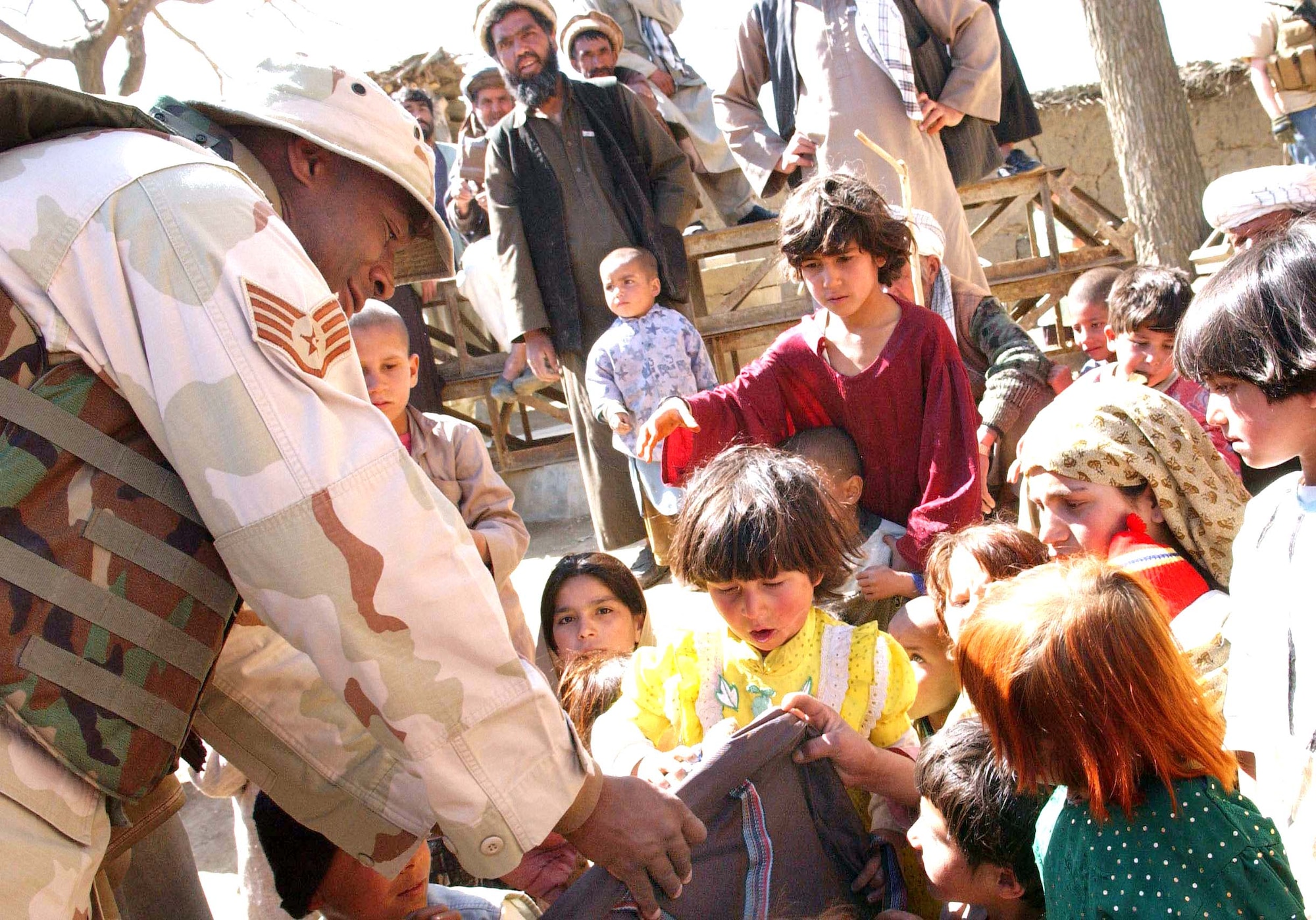 JA FARKEL, Afghanistan - Staff Sgt. Larenzo Smartt hands a bag of school supplies to an Afghan girl during an Adopt-A-Village visit here.  He is an administrator with the 455th Expeditionary Mission Support Group at nearby Bagram Air Base.  (U.S. Air Force photo by Capt. Catie Hague)