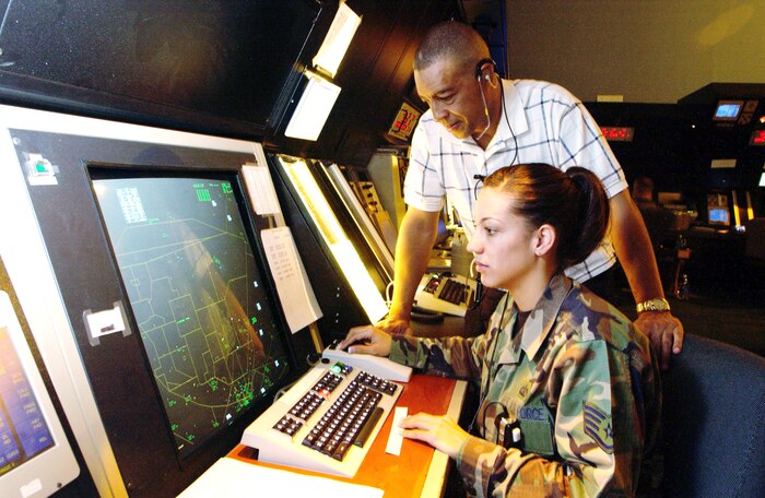 NELLIS AIR FORCE BASE, Nev. -- Retired Chief Master Sgt. Tom Miller looks over his daughter's shoulder, Staff Sgt. Deniece Miller, as they view a radar screen at the air traffic control facility here.  They are assigned to the 57th Operations Support Squadron here.  (U.S. Air Force photo by Tech. Sgt. Demetrius Lester)                        