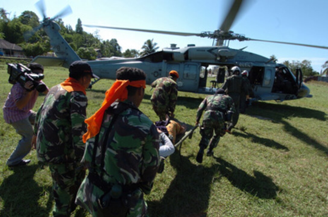 Indonesian soldiers carry an Indonesian woman to a waiting U.S. Navy MH-60 Knighthawk helicopter for airlifting from Nias, Indonesia, to the hospital ship USNS Mercy (T-AH 19) on April 6, 2005. Mercy and the combat stores ship USNS Niagara Falls (T-AFS 3) are currently operating off the coast of Nias, providing medical and humanitarian assistance to victims of the March 28, 2005, 8.7-magnitude earthquake. The helicopter and crew are assigned to Helicopter Combat Support Squadron 5 aboard the Niagara Falls. 