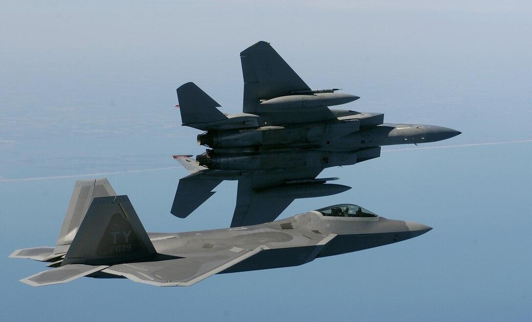 OVER THE ATLANTIC OCEAN -- An F-15 Eagle banks left while an F/A-22 Raptor flies in formation en route to a training area off the coastline of Virginia on April 5.  The 27th Fighter Squadron is performing regular operations with two Raptors on loan from Tyndall Air Force Base, Fla.  The first Langley AFB, Va., F-22 is due to arrive within the next month. The F-15 is assigned to the 1st Fighter Wing at Langley AFB. (U.S. Air Force photo by Tech. Sgt. Ben Bloker)

