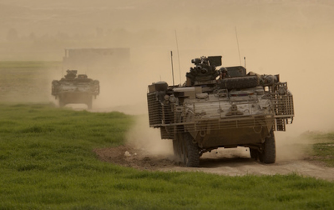 Army Stryker vehicles of the Stryker Brigade Combat Team kick up plumes ...