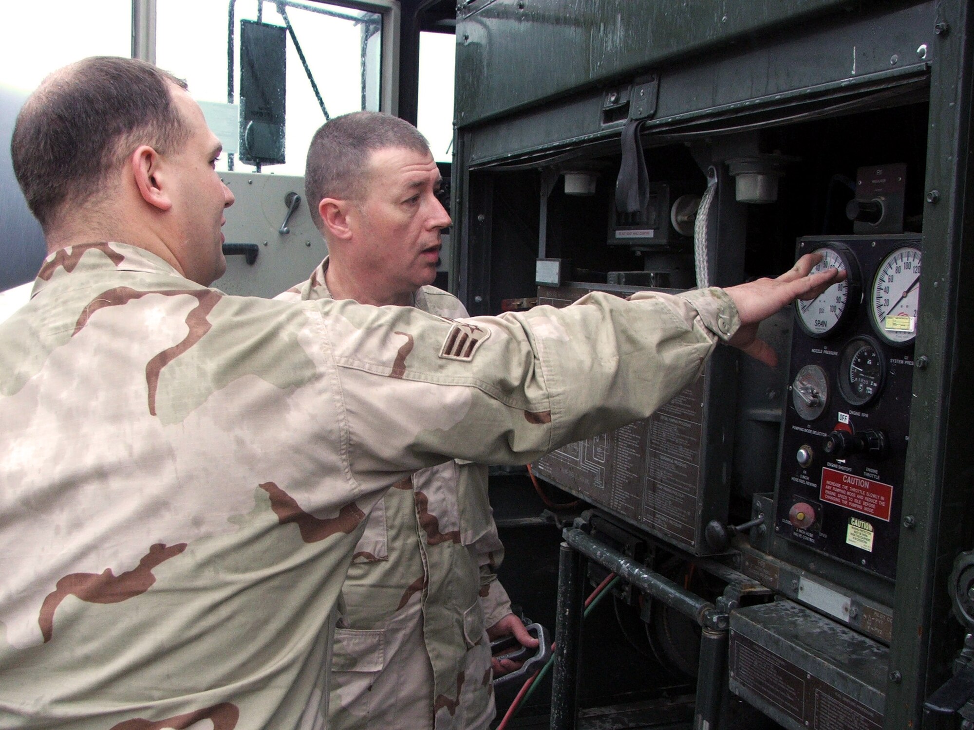 KARSHI-KHANABAD AIR BASE, Uzbekistan -- Senior Airman Seth Rindo shows Army Sgt. 1st Class Gustave Bloom how a fuels truck is set up to pump fuel to aircraft.  Airman Rindo is with the 416th Expedtionary Mission Support Squadron fuels management flight and is deployed from Grand Forks Air Force Base, N.D.  Sergeant Bloom is the fuels accountability officer for Logistics Task Force 191 here.  (U.S. Air Force photo by Tech. Sgt. Scott T. Sturkol)