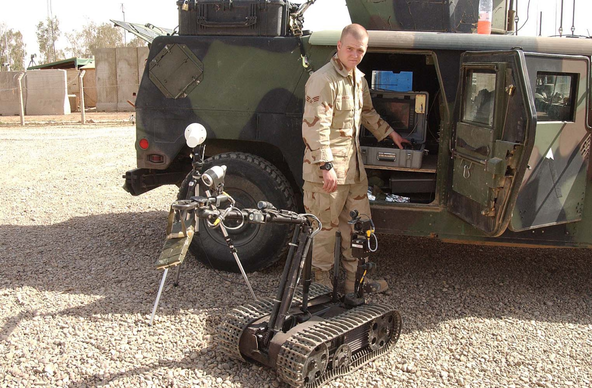 BALAD AIR BASE, Iraq -- Senior Airman Chris Johnson demonstrates how "Angela" works by having the robot hold C4 explosives.  He is a 332nd Expeditionary Civil Engineer Squadron explosive ordnance disposal technician here.  The robots can disassemble improvised explosive devices and perform reconnaissance by searching the area for more hazards.  (U.S. Air Force photo by Senior Airman Colleen Wronek)                   