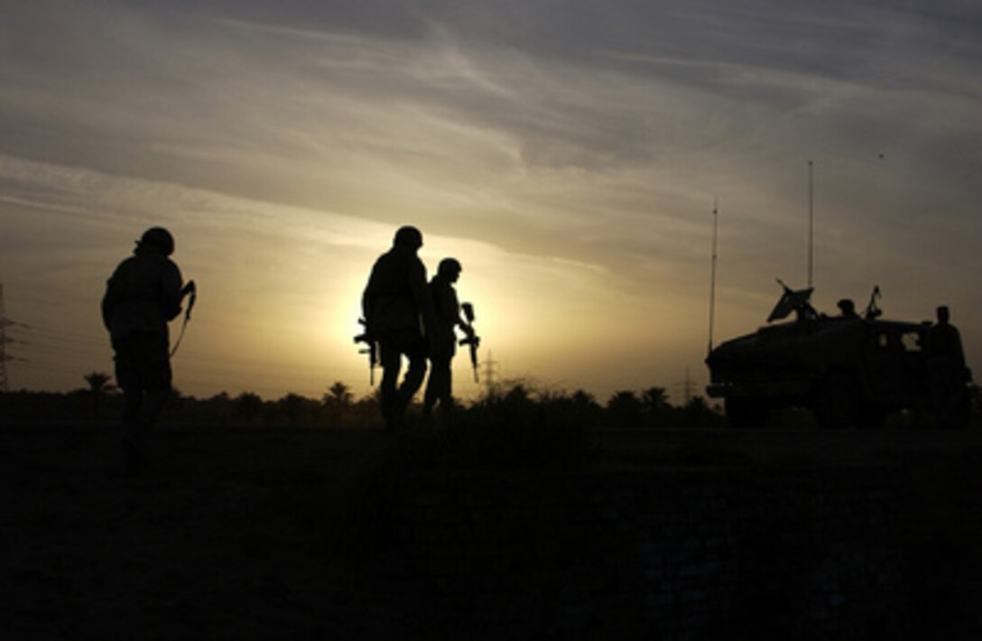 U.S. soldiers from the 1st Battalion, 155th Brigade Combat Team and Marines from the 2nd Air Naval Gunfire Liaison Company walk back to their Humvees after searching through a field for an insurgent mortar pit in Al Iskandariyah, Iraq, on March 29, 2005. 