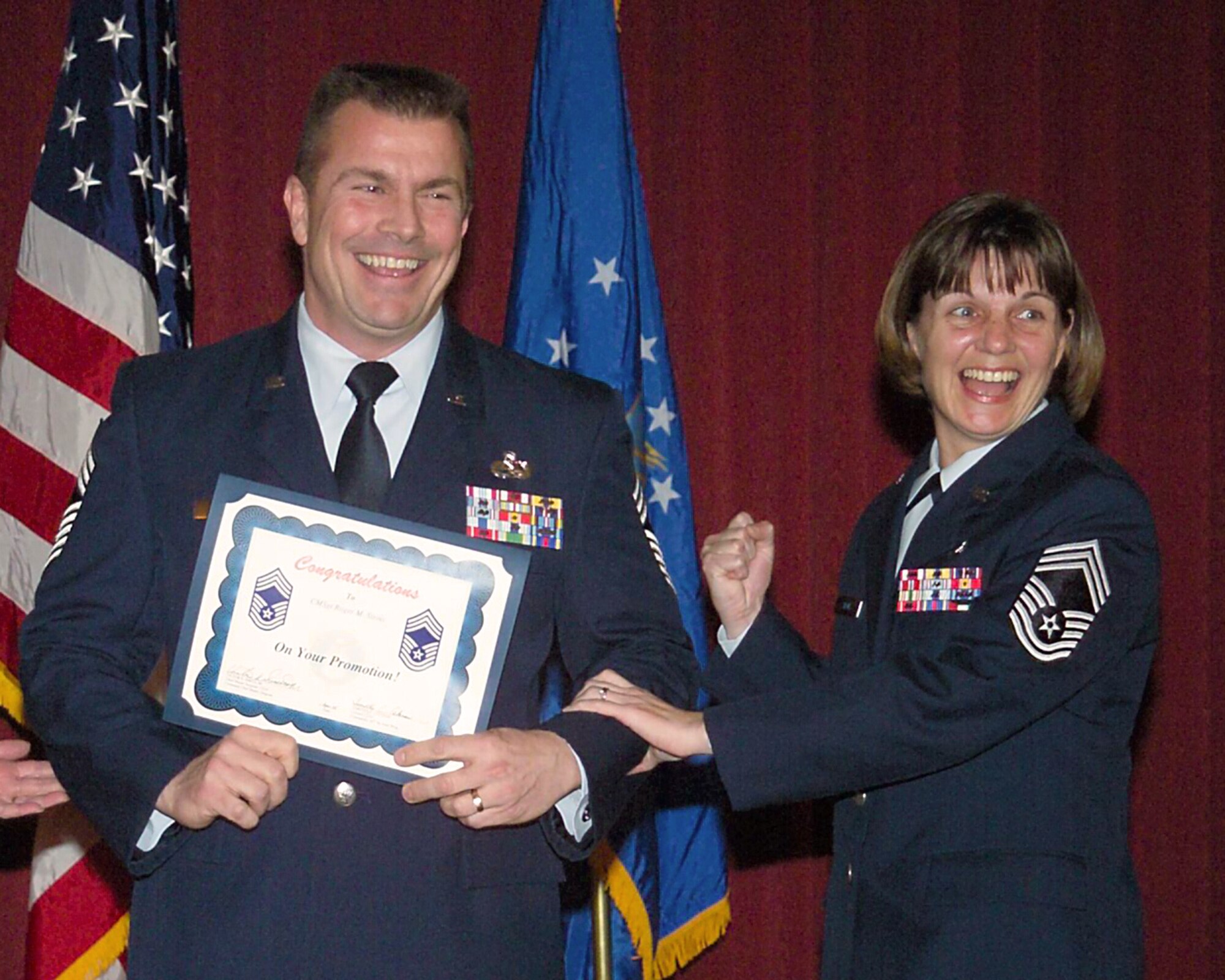 HANSCOM AIR FORCE BASE, Mass. -- Chief Master Sgt. Lisa Sirois tacks chief master sergeant stripes on her husband, Roger Sirois, during his promotion ceremony here.  The two married after high school in 1980 and then joined the Air Force together.  (U.S. Air Force photo by Linda LaBonte Britt)