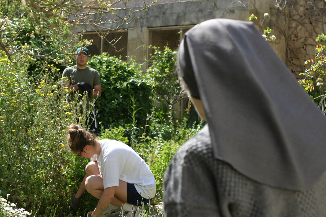 Mother Superior Marie-Rose Agius of the Fatima House young women's hostel in Sliema, Malta helps Religious Programmer 2nd Class 2nd Class Roberto Barney with MSSG-26 and Fire Controlman 2nd Class Corinne Korschell from the ship landing dock USS Ashland (LSD 48) pull weeds from a backyard garden during a community service project April 13th.  (Official photo by Sgt. Mario Gonzalez)