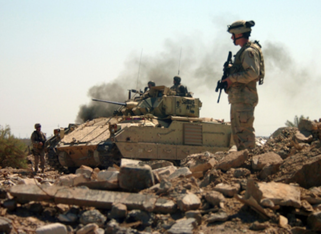 U.S. Army soldiers and a Bradley Fighting Vehicle with the 2nd Battalion, 11th Armored Cavalry Regiment cautiously advance into a bunker area as they conduct a raid on the Hateen Weapons Complex in Babil, Iraq, on March 26, 2005. The 11th Armored Cavalry is attached to the 155 Brigade Combat Team headquartered in Tupelo, Miss. 