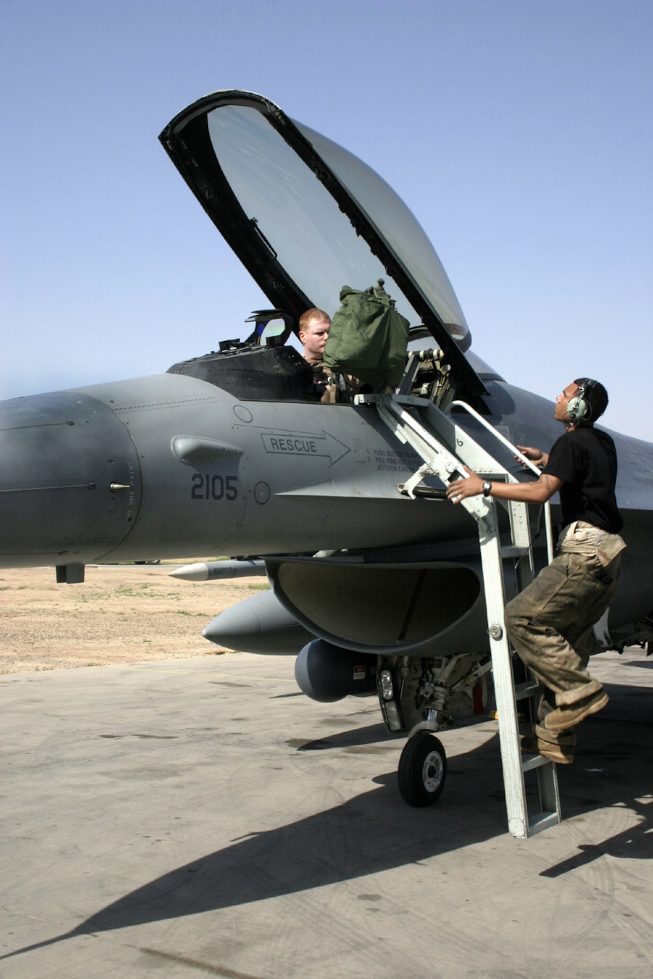 BALAD AIR BASE, Iraq -- Senior Airman Frankie Jordan helps Capt. Andy Stockman with his bag upon the captain's return from a mission.  Airman Jordan is a crew chief with the 332nd Expeditionary Aircraft Maintenance Squadron here, and Captain Stockman is an F-16 Fighting Falcon pilot with the 34th Expeditionary Fighter Squadron.  (U.S. Air Force photo by Staff Sgt. Adam Bradford)