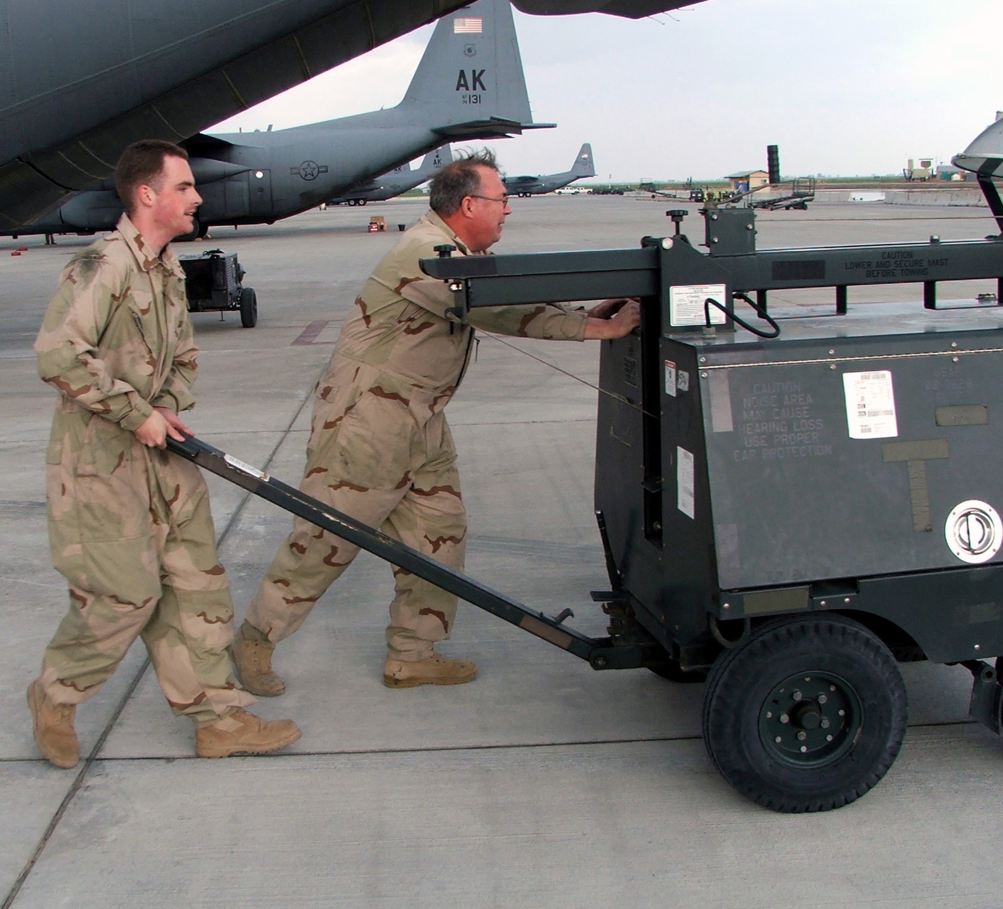 KARSHI-KHANABAD AIR BASE, Uzbekistan -- Senior Airman Shawn Younger (left) and Staff Sgt. David Baker move a portable flood light while working on a C-130 Hercules here April 8.   Airman Younger is a C-130 crew chief deployed from Elmendorf Air Force Base, Alaska.  Sergeant Baker is a C-130 metals fabrication craftsman with the 774th Expeditionary Airlift Squadron and is deployed from the West Virginia Air National Guard at Charleston.  (U.S. Air Force photo by Tech. Sgt. Scott T. Sturkol)