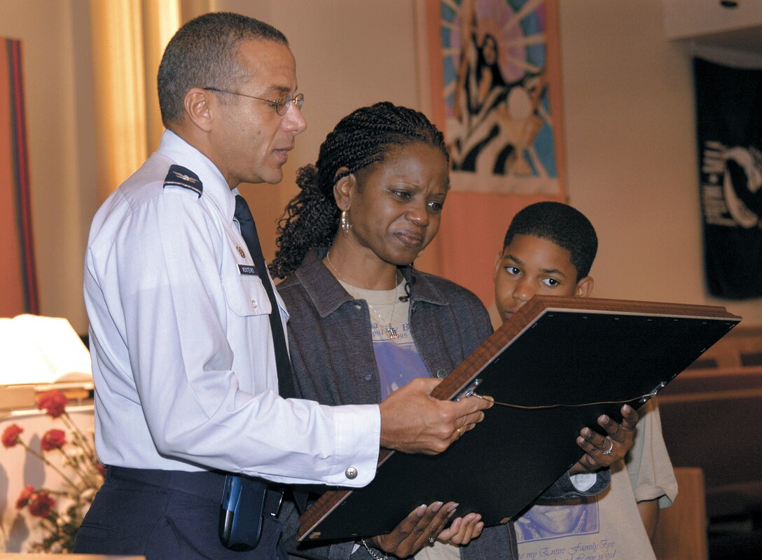 TINKER AIR FORCE BASE, Okla. -- Col. Andrew Monteiro Jr. presents Constance Favorite with a plaque showing the medical group's memorial to her daughter, Airman 1st Class Lakesha Levy, who was killed in the Alfred P. Murrah Federal Building bombing April 19, 1995.  Airman Levy worked in the base laboratory, but was visiting the Oklahoma City federal building when it exploded.  Along with Airman Levy's mother, about 50 family members, including her 12-year-old son, Corey Levy (pictured), visited here April 18 to see the base's bombing memorial, attend a service at the base chapel and see the lab where Airman Levy worked.  Colonel Monteiro is the 72nd Medical Group commander.  (U.S. Air Force photo by Margo Wright)