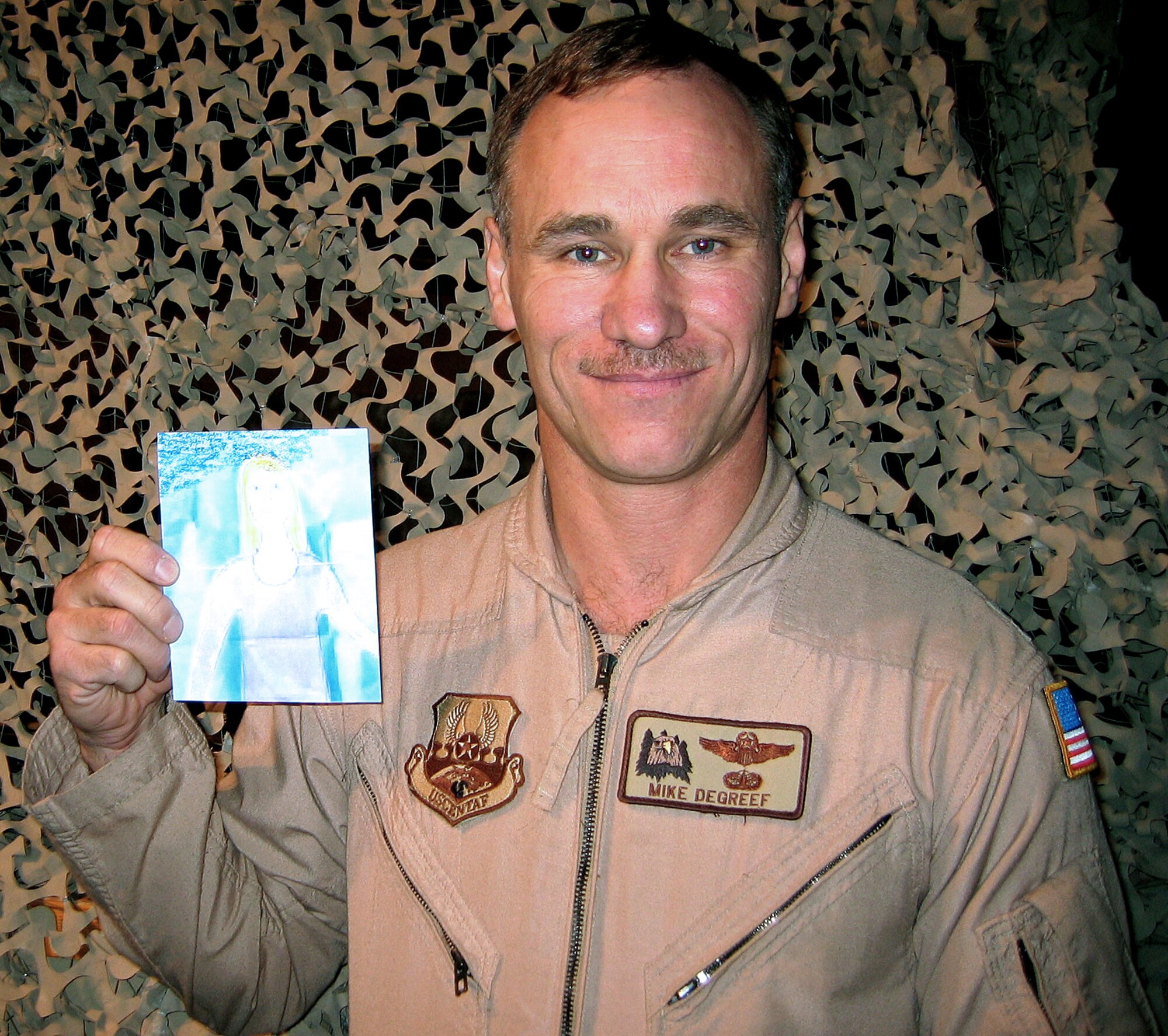 MANAS AIR BASE, Kyrgyzstan -- Lt. Col. Mike DeGreef poses with his well-traveled "Mini Alyssa," a copy of a picture his 9-year-old daughter drew of herself.  He is assigned to the 22nd Expeditionary Air Refueling Squadron here and is from Fairchild Air Force Base, Wash.  (Department of Defense photo by Kathleen T. Rhem)