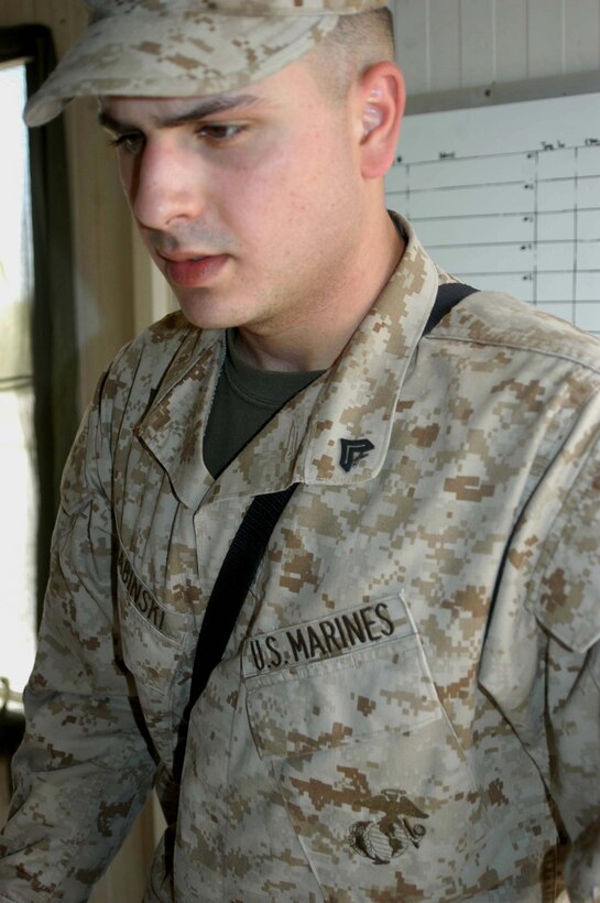 CAMP HURRICANE POINT, Ar Ramadi, Iraq (April 29, 2005) -Corporal Dan L. Grabinski, legal administrative clerk with Headquarters and Service Company, 1st Battalion 5th Marine Regiment, fills his secondary billet as the day non commissioned officer in-charge of the detainee facility here. The 21-year-old from Schiller Park, Ill., processes expected insurgents his fellow infantry battalion leathernecks snatched up out of the city while conducting security and stabilization missions. With help from three other Marines, Grabinski runs the detainees through the biometric automative tools system, which helps them distinguish members of the insurgency from innocent Iraqi civilians. Detainees found guilty of committing terrorist acts are sent to the Abu Ghraib Prison. Photo by Cpl. Tom Sloan