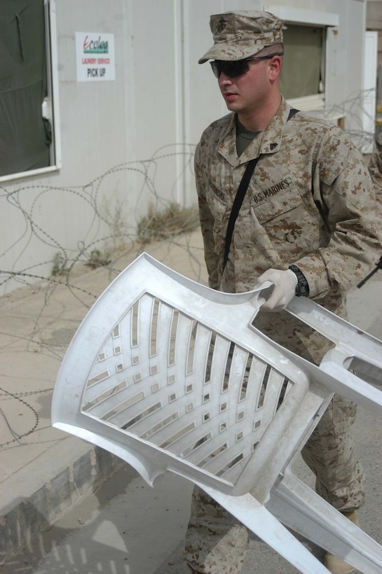 CAMP HURRICANE POINT, Ar Ramadi, Iraq (April 29, 2005) -Corporal Dan L. Grabinski, legal administrative clerk with Headquarters and Service Company, 1st Battalion 5th Marine Regiment, carries a chair for detainees to sit in during their stay at the detainee facility here. The 21-year-old from Schiller Park, Ill., is also the day non commissioned officer in-charge of the detainee facility. He processes expected insurgents his fellow infantry battalion leathernecks snatched up out of the city while conducting security and stabilization missions. With help from three other Marines, Grabinski runs the detainees through the biometric automative tools system, which helps them distinguish members of the insurgency from innocent Iraqi civilians. Detainees found guilty of committing terrorist acts are sent to the Abu Ghraib Prison. Photo by Cpl. Tom Sloan