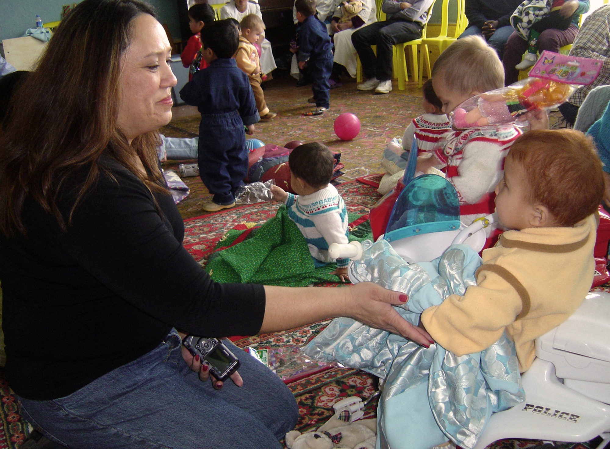 QITAB, Uzbekistan -- Tech. Sgt. Lisa Ramos gives a quilt she made to an Uzbek child during a humanitarian assistance visit to a baby orphanage here.  Airmen, Soldiers and civilians from nearby Karshi-Khanabad Air Base visited the orphanage and handed out handmade baby quilts, baby formula, diapers, clothes and toys.  Sergeant Ramos is assigned to the 416th Expeditionary Mission Support Squadron's communications flight and is deployed from Vandenberg Air Force Base, Calif.  (U.S. Air Force photo by Tech. Sgt. Scott T. Sturkol)