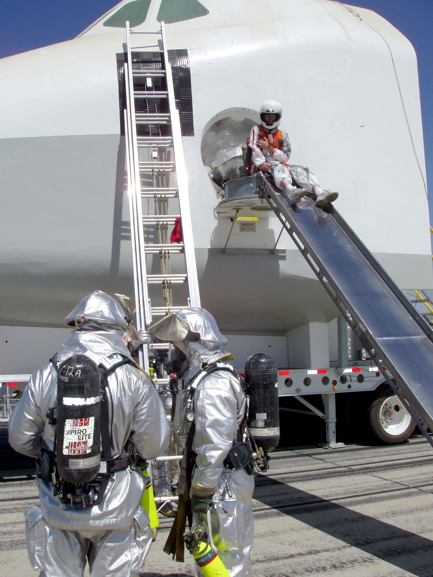 EDWARDS AIR FORCE BASE, Calif. -- Firefighters with the 95th Air Base Wing's fire protection division wait for a shuttle crewmember to slide down the side hatch.  During the mock landing, the shuttle crew reported smoke in the cockpit.  (U.S. Air Force photo by Senior Airman Matthew Dillier)