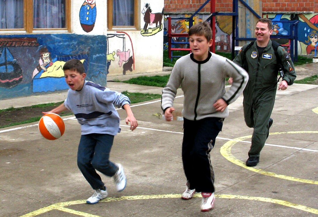 PRISTINA, Serbia and Montenegro -- Maj. Brian Benson plays basketball with children during a recent visit to the Pristina Mother and Child Center here.  He is assigned to Kosovo Force headquarters at NATO Base Film City.  (U.S. Air Force photo by Master Sgt. Lee Roberts)
