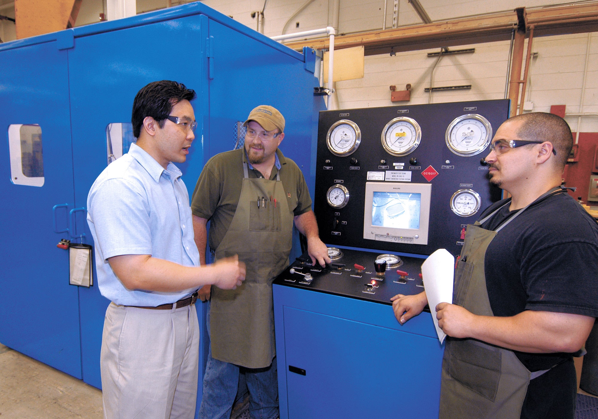 TINKER AIR FORCE BASE, Okla. -- Chris Truoccolo (right) and Russell Keene discuss the safer test stand that Don Ngo (left) designed so aircraft parts could be pressure tested while technicians remain protected in case of explosions.  They are with the Tank and Cooler Unit at the Oklahoma City Air Logistics Center here.  (U.S. Air Force photo by Margo Wright)