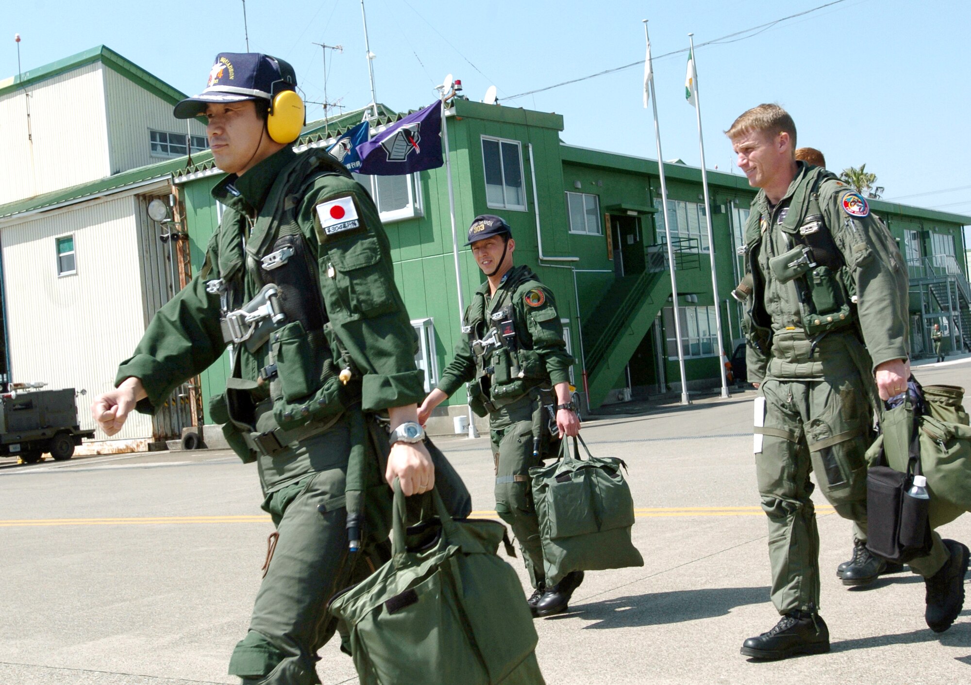 NYUTABARU AIR BASE, Japan -- (From left) Japanese Majs. Yasuhiro Sudo and Kouji Takada walk with Maj. Brian Bergeron as they prepare for an afternoon mission during hands-on air-to-air refueling training here.  Japanese F-15 Eagle pilots, under the watchful eye of U.S. Airmen, are getting trained to qualify in aerial refueling.  Major Bergeron is an instructor pilot with the 325th Operations Support Squadron at Tyndall Air Force Base, Fla.  (U.S. Air Force photo by Master Sgt. Val Gempis)