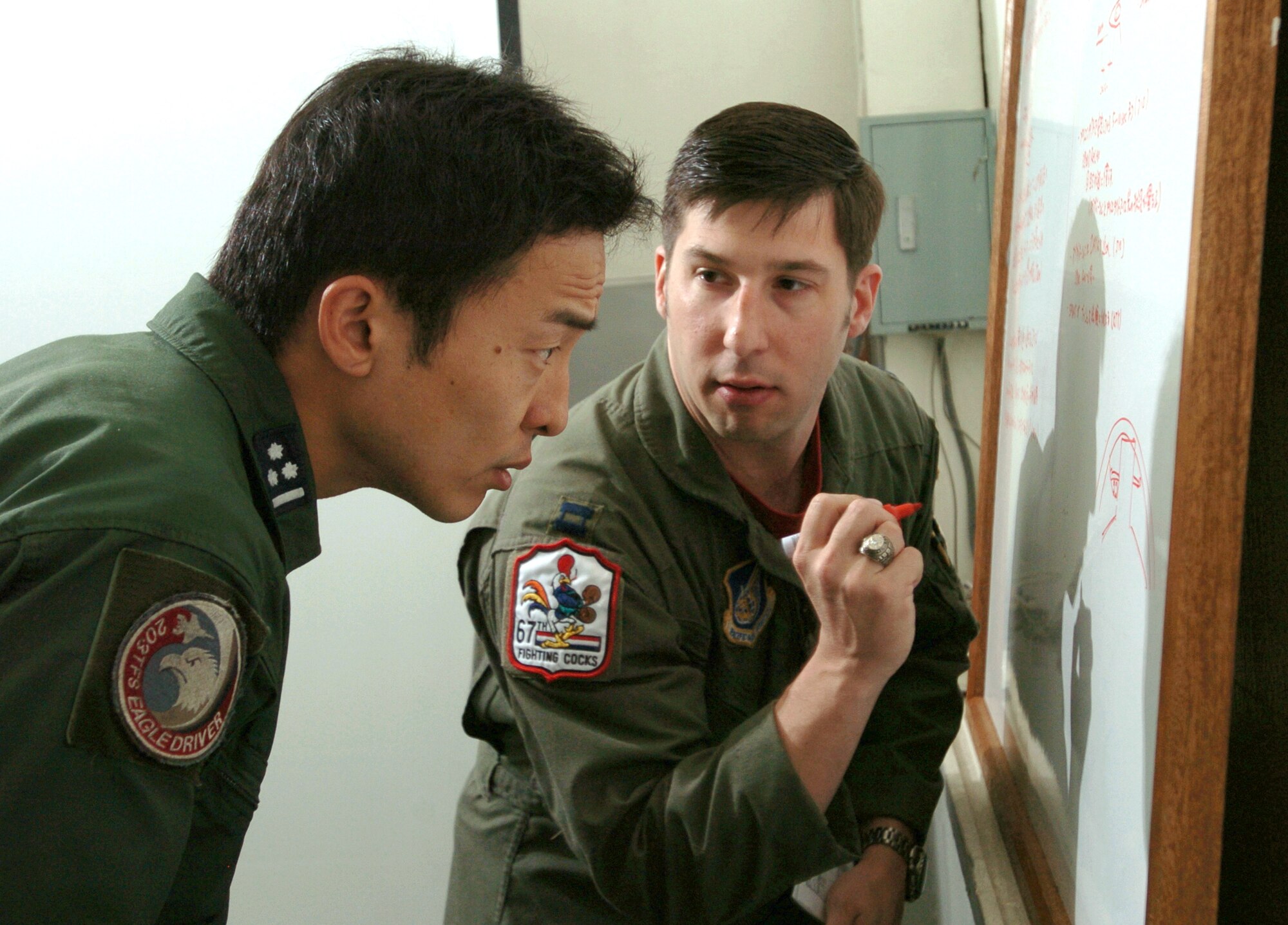 NYUTABARU AIR BASE, Japan -- Capt. Tony Dicarlo and Japanese Capt. Masato Miyake discuss flight tactics before hands-on air-to-air refueling training here.  Japanese F-15 Eagle pilots, under the watchful eye of U.S. Airmen, are getting trained to qualify in aerial refueling.  Captain Dicarlo is an F-15 pilot with the 67th Fighter Squadron at Kadena Air Base, Japan.  (U.S. Air Force photo by Master Sgt. Val Gempis)