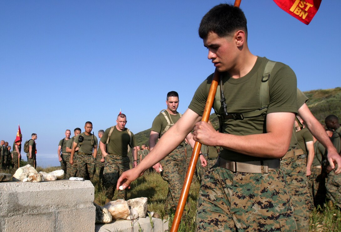 A Marine from 1st Battalion, 4th Marine Regiment, places a white stone at the base of a memorial site for Marines from 1st Marines that died during Operation Iraqi Freedom I and II outside of Camp Horno, April 26. Every Marine that hikes up San Onofre Mountain to the memorial carries a white stone to place at the memorial's base.