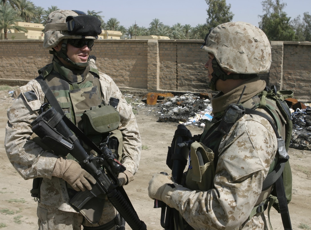 SAQLAWIYAH, Iraq - Sgt. Matthew E. Dreher, civil affairs Marine with Team 3, Detachment 2, 5th Civil Affairs Group, speaks with Cpl. Tyler R. Allamong, another CAG Marine, at the medical clinic here April 28.  Dreher's CAG helps the community here by meeting with local leadership to assess their needs and work with Iraq's new government to help rebuild the country's infrastructure.