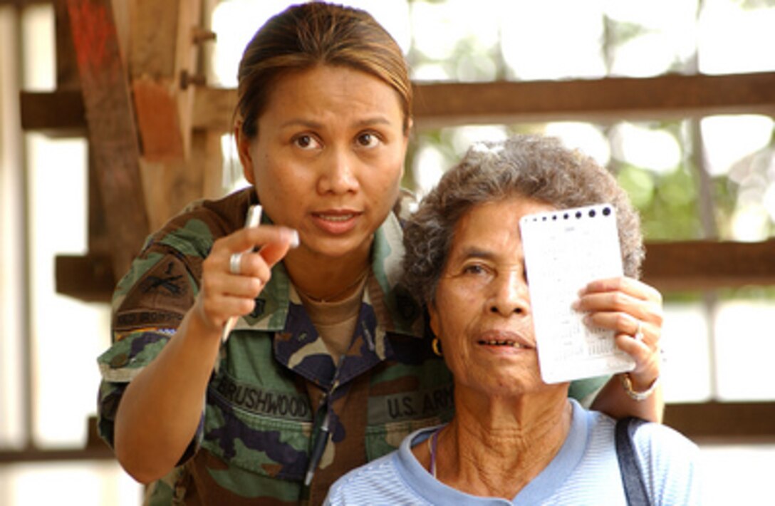 U.S. Army Staff Sgt. Siriporn Brushwood conducts an eye exam on a Thai woman so she can get a pair of glasses in Huey Geung, Thailand, in support of a Medical Capabilities exercise during Exercise Cobra Gold '05 on April 25, 2005. Brushwood is deployed to Thailand for the joint-combined exercise from the 351st Civil Affairs Command. 