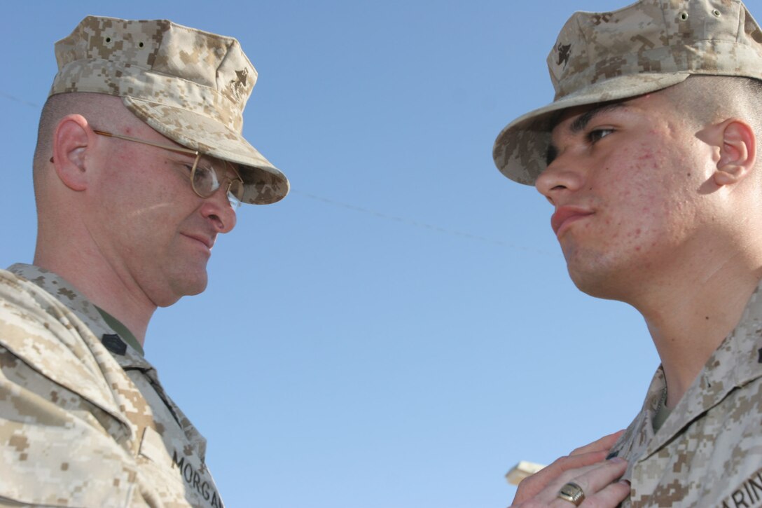 AL ASAD, Iraq ? Gunnery Sgt. Ronald Morgan, a company gunnery sergeant with the Provisional Security Battalion, pins Cpl. Roman Sena, a field military policeman with security battalion and Columbus, Ohio, native, during his promotion ceremony here Aug. 1. Morgan was Sena?s senior drill instructor at boot camp in 2002 at Marine Corps Recruit, Depot Parris Island, S.C.