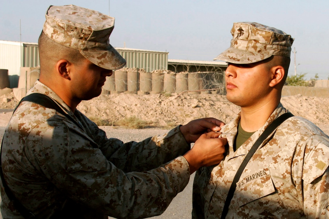 CAMP FALLUJAH, Iraq - Sergeant Teddy Straub pins rank insignia on Cpl. Robert E. Straub's collar during a promotion ceremony Aug. 1.  The brothers, from Ontario, Calif., are deployed to different locations in Iraq and don't see each other often because of deployments in support of the Global War on Terrorism and other operational commitments.