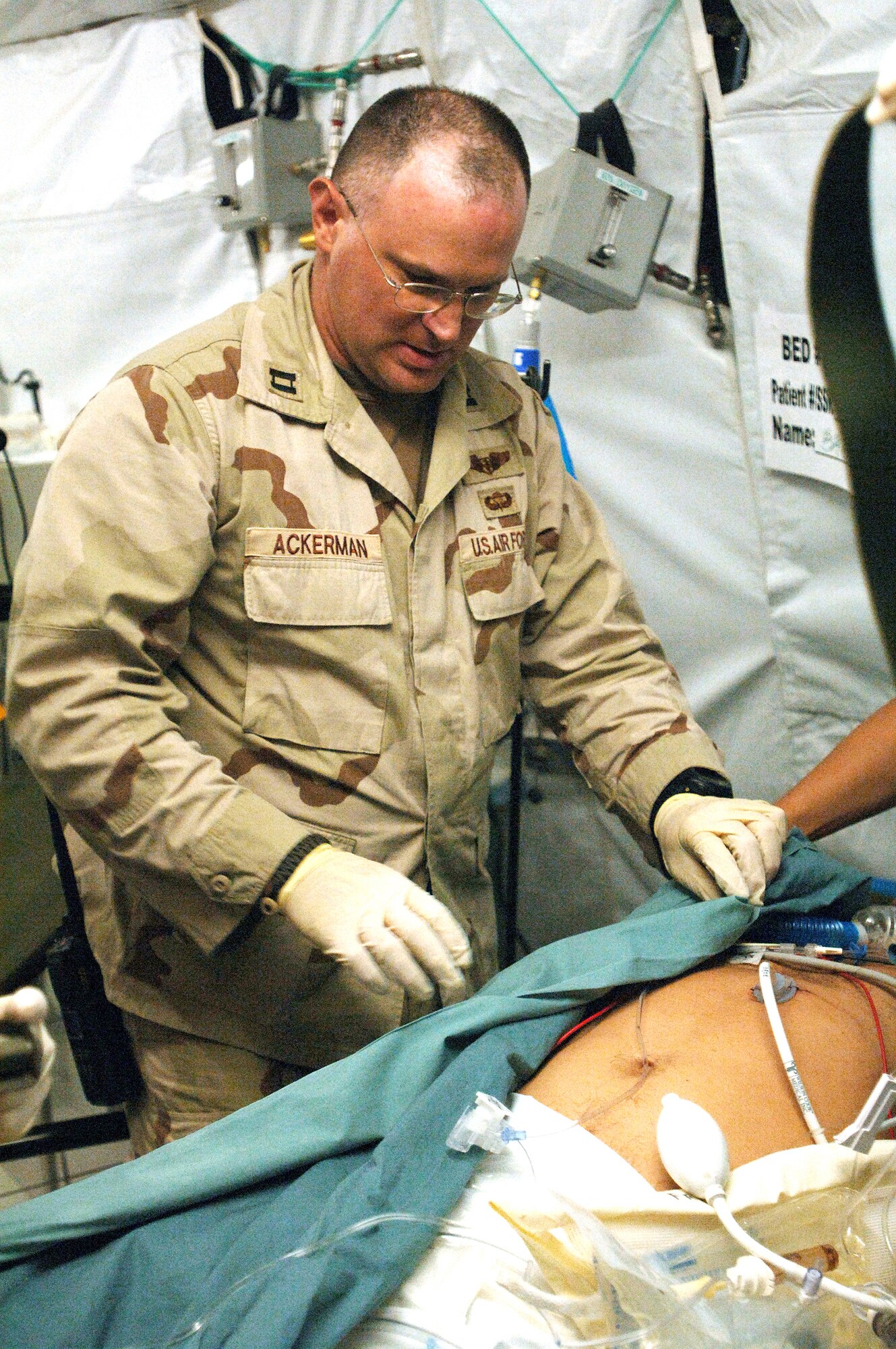 BALAD AIR BASE, Iraq -- Capt. Brian Ackerman checks a patient's dressing and equipment to ensure he is ready for flight.  His job is to coordinate the movement of critically wounded patients between the Air Force theater hospital here and the contingency aeromedical staging facility.  Captain Ackerman is a nurse with the 379th Expeditionary Aeromedical Evacuation Squadron.  (U.S. Air Force photo by Staff Sgt. Chad Chisholm)