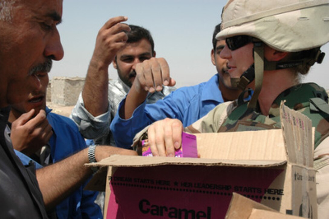 Air Force Capt. Michelle Harwood hands out boxes of cookies to construction workers during renovations at the Hamdan Police Station in Basrah, Iraq, on July 27, 2005. 