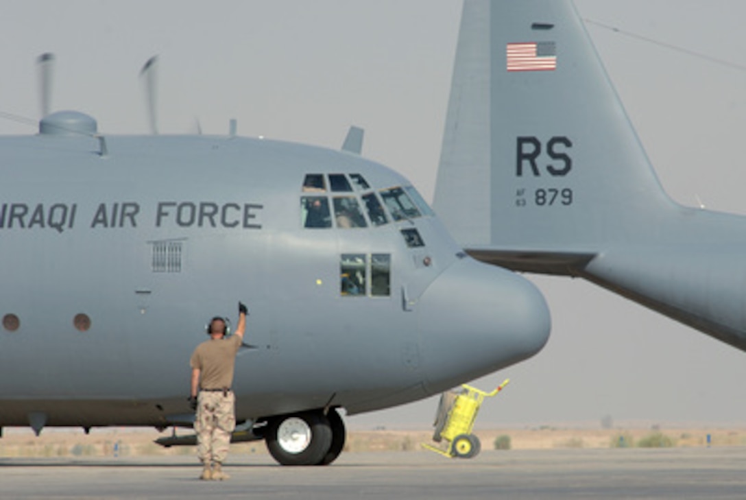 A U.S. Air Force C-130 Hercules crew chief gives the flight crew of an Iraqi Air Force C-130 Hercules a thumbs-up as they launch on a training mission from Ali Base, Iraq, on July 27, 2005. The Hercules crew chief is attached to the 777th Expeditionary Maintenance Squadron. 