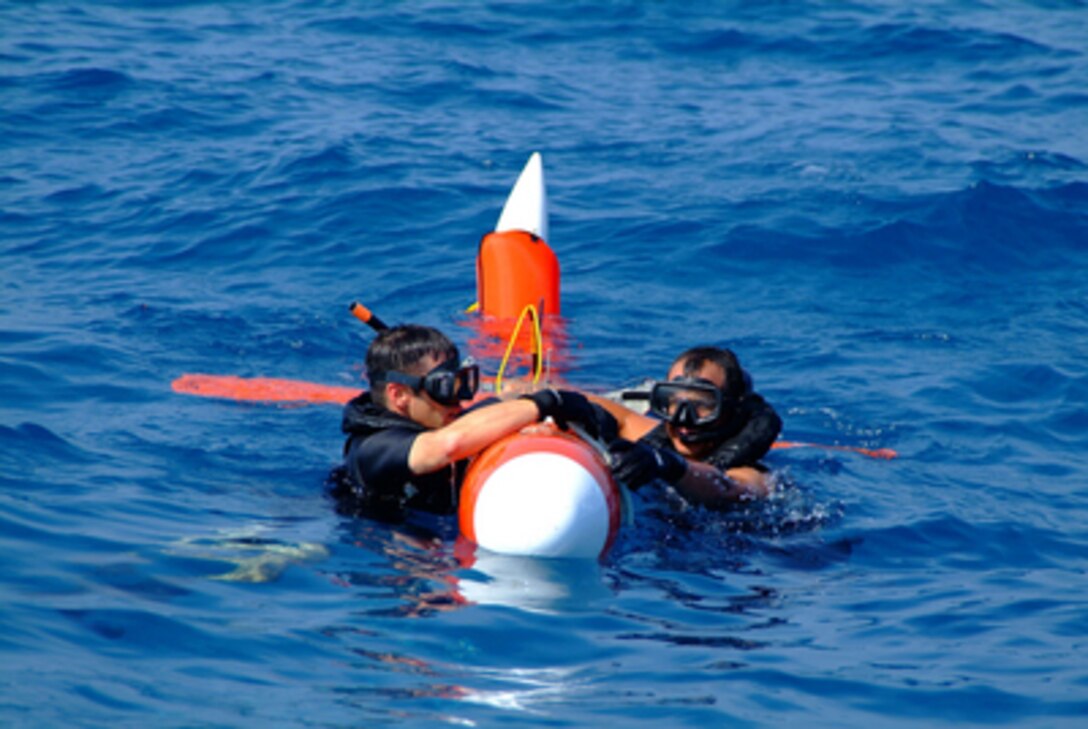 Navy Petty Officers 2nd Class Jeremy R. Spaulding and Gerardo Arbulu retrieve a BQM-74E aerial drone following an air defense exercise with U.S. and Indonesian naval forces during exercise Cooperation Afloat Readiness and Training underway in the Java Sea on July 28, 2005. Spaulding and Gerardo Arbulu are both search and rescue swimmers assigned to the dock landing ship USS Harpers Ferry (LSD 49). The training is a regularly scheduled series of bilateral military training exercises with several Southeast Asia nations designed to enhance interoperability of the respective sea services. 