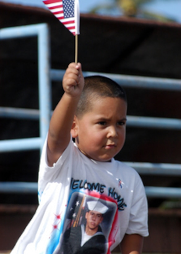 The son of a sailor waves an American flag to welcome home his father stationed aboard the guided missile destroyer USS O'Kane (DDG 77) as the ship returns to Pearl Harbor, Hawaii, from a six-month deployment on July 29, 2005. O'Kane was deployed as part of the USS Carl Vinson (CVN 70) Carrier Strike Group in support of the war on terror. 