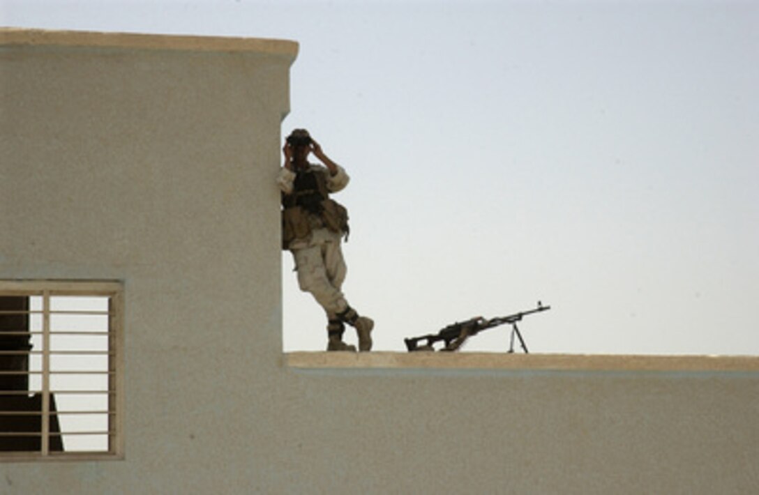 An Iraqi Army soldier scans the surrounding area through binoculars as he provides security from the top of a school in West Baghdad, Iraq, on July 23, 2005. Soldiers from the U.S. Army's 3rd Infantry Division and the Iraqi Army are securing the perimeter of the school so that medical assistance can be provided for the local population. 