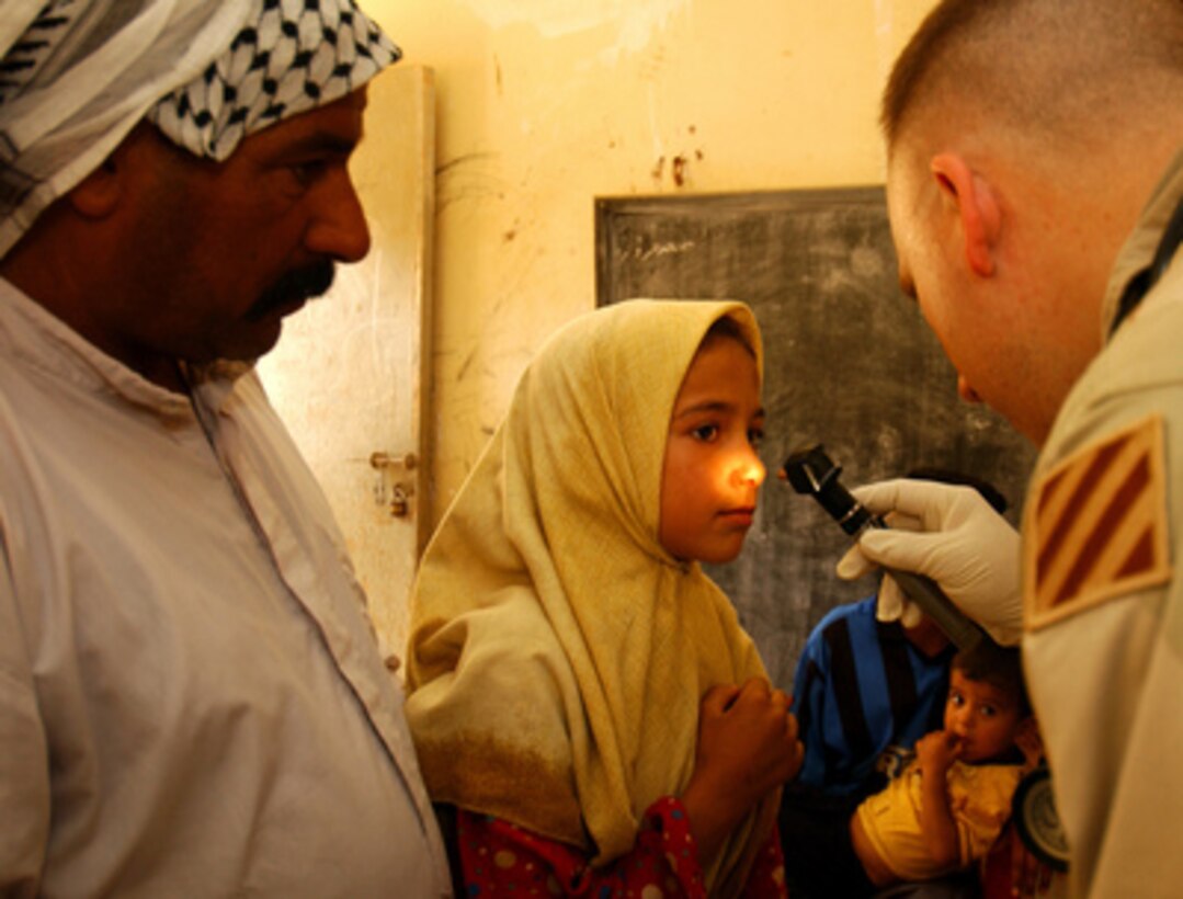 U.S. Army Capt. Arne Oas (right) examines a swelling on a young girl's nose during a Medical Civil Action Program at Fenjan Village near Baghdad, Iraq, on July 26, 2005. Oas is assigned to the 3rd Squadron, 7th Cavalry Regiment, whose medical staff provides periodic health care and assistance to civilians in different locations. 