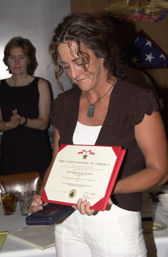 Julie Shumney, the wife of posthumous Bronze Star recipient 2nd Platoon, Charlie Company, Battalion Landing Team, 1st Battalion, 3rd Marine Regiment, 3rd Marine Division, III Marine Expeditionary Force, 1st Lt. Dustin M. Shumney silently pauses as a crowd of Marine Corps supporters applaud at a ceremony held in her familiy's honor.  Lt. Shumney was killed in a helicopter crash one month after his heroic actions during Operation Al Fajr in Fallujah, Iraq.
