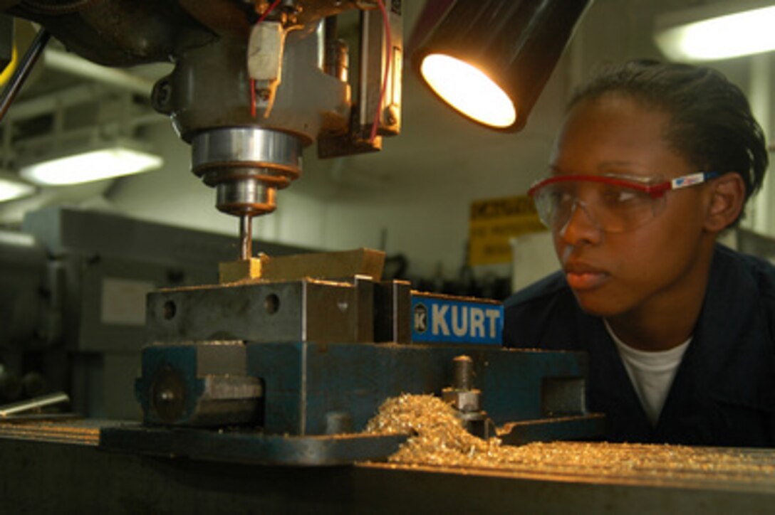 U.S. Navy Fireman Apprentice Antoinette Marshall uses a milling machine in the machine repair shop aboard the USS Kitty Hawk (CV 63) to fabricate a replacement clamp while at sea on Aug. 3, 2005. Marshall, from Huntsville, Texas, is a Navy machinery repairman aboard the aircraft carrier. Machinery repairmen aboard the Kitty Hawk cut, shape and finish various metals to fix or replace broken parts to keep the ship's equipment running. 