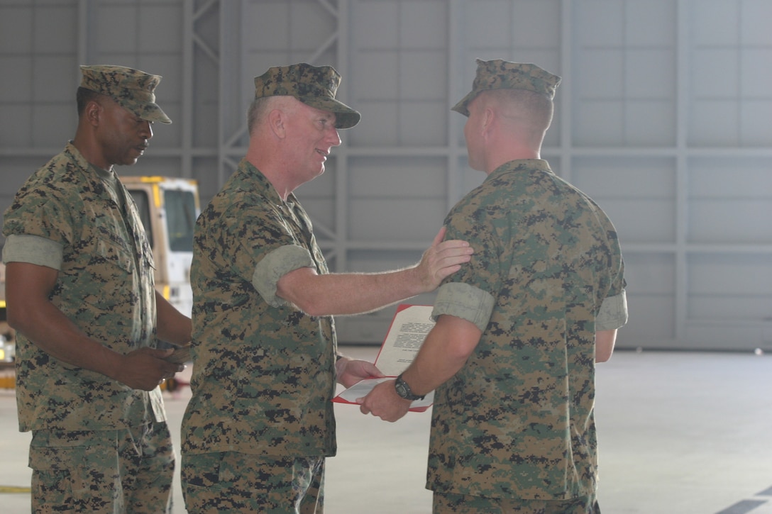 Brig. Gen. George J. Trautman III (center), commanding general, 1st Marine Aircraft Wing, Japan, congratulates Lt. Col. Justin M. Wisdom, former commanding officer of Helicopter Training Squadron 301 and current executive officer of Marine Aircraft Group 24, after presenting him with the Navys Chief of Operations 2004 Naval Aviation Safety Award.