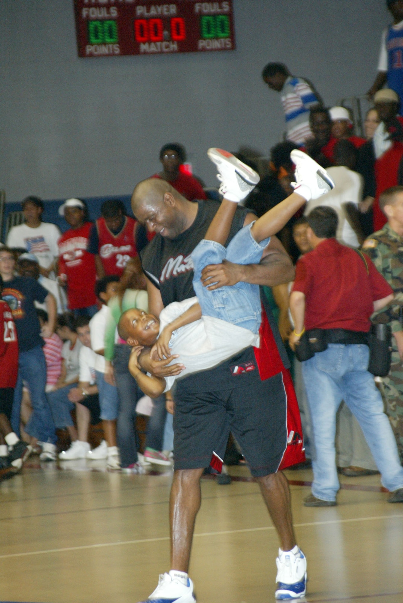 FORT BRAGG, N.C. -- Qunicy Lewis, 10, gets a lift from NBA great, Earvin "Magic" Johnson July 29 during an exhibition basketball game here.  Four Airmen from nearby Pope Air Force Base were part of a combined Air Force and Army basketball team that challenged Mr. Johnson and his team of former NBA professionals.  (U.S. Air Force photo by Lisa Terry McKeown)