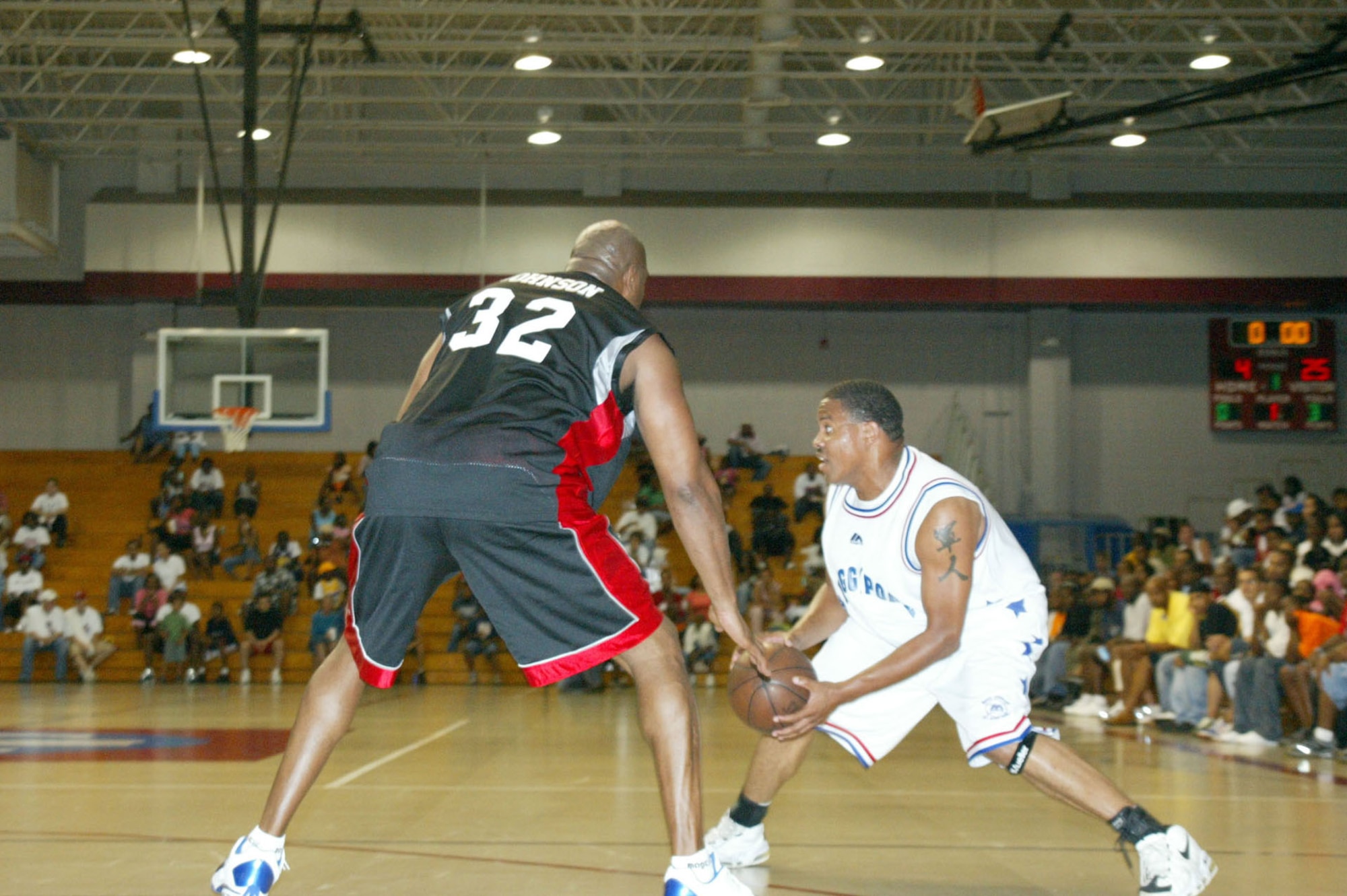 FORT BRAGG, N.C. -- Staff Sgt. Greg Streeter tries to play around Earvin "Magic" Johnson's defenses in an exhibition basketball game here July 29.  Sergeant Streeter and three other Airmen from nearby Pope Air Force Base were part of a combined Air Force and Army basketball team that faced Mr. Johnson and his team of former NBA professionals.  Sergeant Streeter is assigned to the 43rd Maintenance Squadron.  (U.S. Air Force photo by Lisa Terry McKeown)