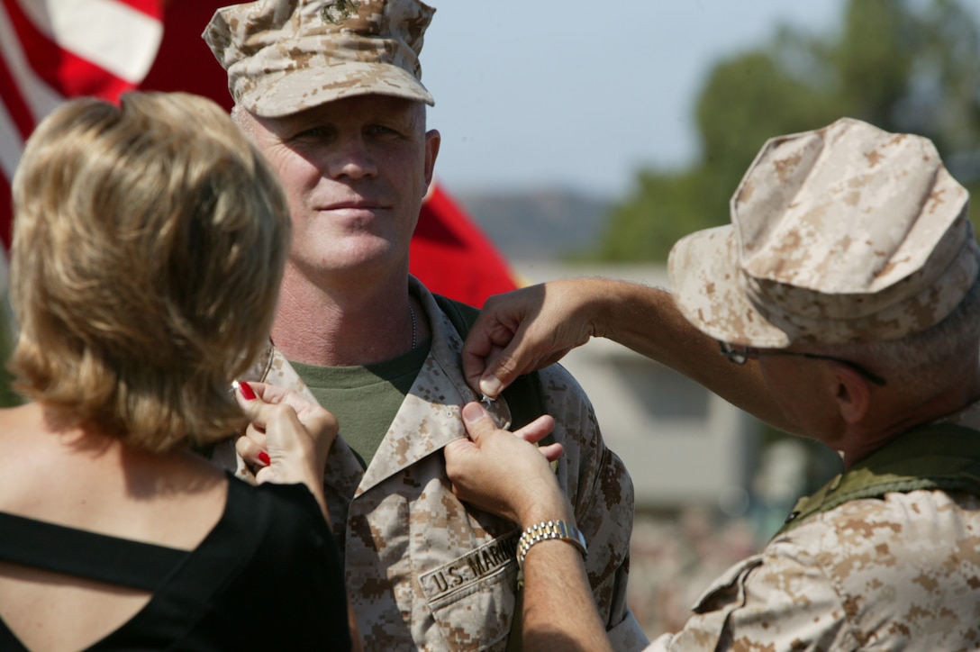 Shortly before assuming command of the 8,900-strong 1st Force Service Support Group, Brig. Gen. David G. Reist was ceremoniously "frocked" to brigadier general by his wife and the outgoing commander, Maj. Gen. Richard S. Kramlich at the 22 Area parade deck Friday.