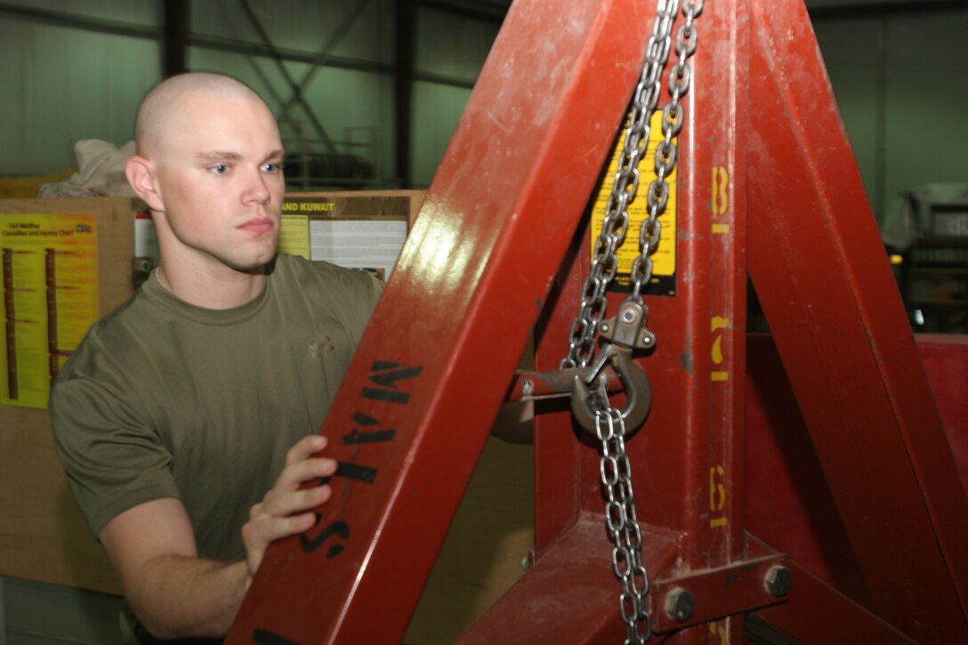 AL ASAD, Iraq - Corporal Douglas Brown, an F/A-18 Hornet mechanic with Marine Aviation Logistics Squadron 26 and Mableton, Ga., native, pushes a pulley system in place as he and another Marine prepare to move an engine container here Aug. 8. Brown has been in the Marine Corps Reserves for six years.