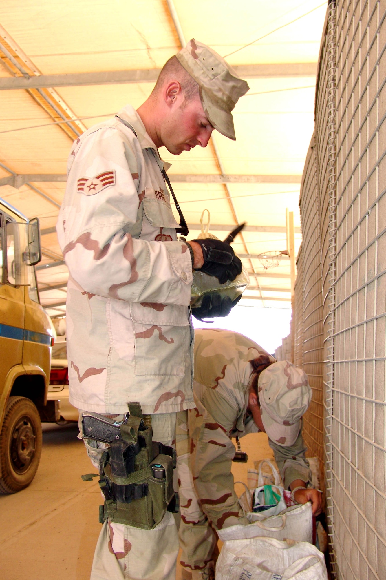 KIRKUK AIR BASE, Iraq -- Senior Airman Jeff George looks in a third-country national's lunchbox to ensure it does not contain contraband.  Search area Airmen search all people and vehicles entering the base.  Airman George is assigned to the 506th Expeditionary Security Forces Squadron here.  (U.S. Air Force photo by Tech. Sgt. J. LaVoie) 