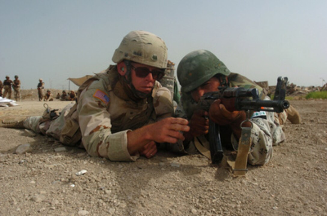 U.S. Army Spc. John Young (left) instructs an 8th Division Iraqi Army soldier during a live fire weapons training exercise on the Iraqi Army compound at Forward Operating Base Iskandariyah, Iraq, on July 28, 2005. Young is a member of the U.S. Army Multinational Training Team, part of the155th Brigade Combat Team, which is providing training to increase the proficiency of Iraqi army soldiers. 