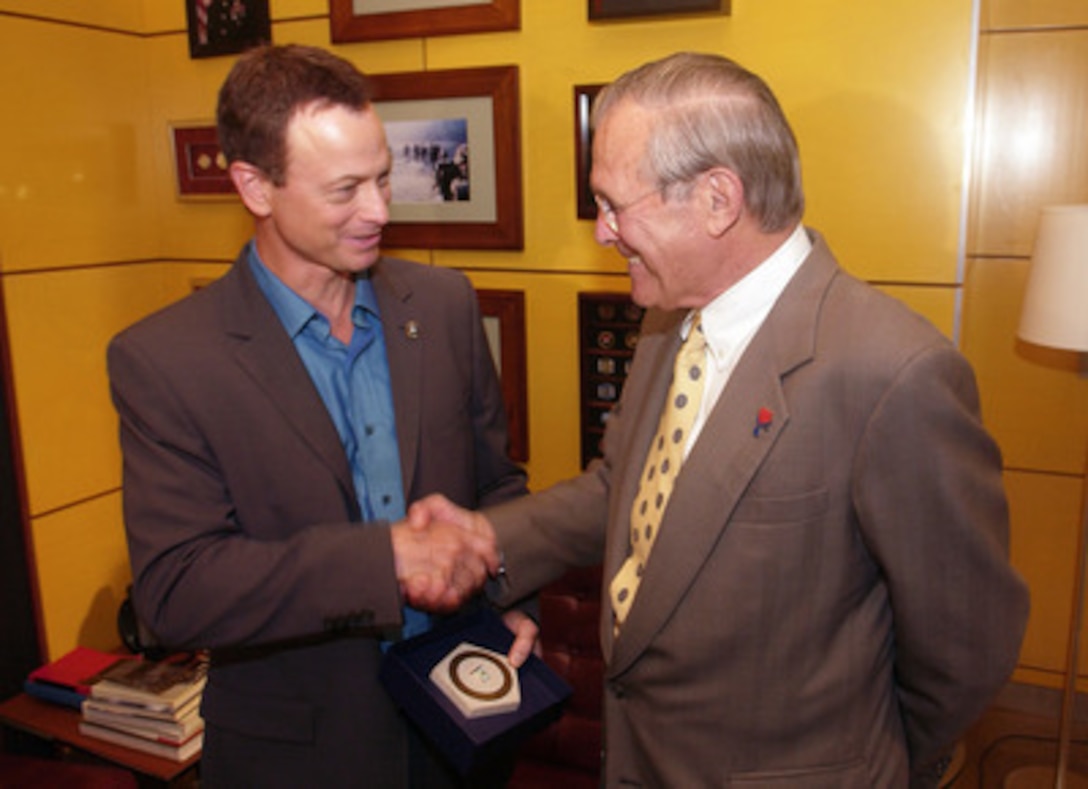 Secretary of Defense Donald H. Rumsfeld (right) presents actor Gary Sinese with an inscribed limestone Pentagon during a visit to the CBS studios in Los Angeles, Calif., on Aug. 4, 2005. Rumsfeld visited the CSI: New York set to thank Sinise personally for his support of the "America Supports You" program through his "Operation Iraqi Children" effort. Sinise co-founded Operation Iraqi Children with Seabiscuit author Laura Hillenbrand. The organization collects and ships school supplies and toys to Iraq for distribution by U.S. troops, providing much- needed materials for Iraqi children while boosting the morale of the service members who pass them out. The limestone used to create the memento is from the original quarry used to build the Pentagon in 1941 and to rebuild the Pentagon after the terrorist attack of Sept. 11, 2001. 
