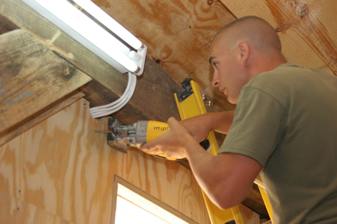 AL ASAD, Iraq ? Sergeant Greg Silas, a combat engineer with Marine Wing Support Squadron 271 and Augusta, Ga., native, prepares to cut away a section of a wall to make room for more wires in the newly constructed Workhorse multi-purpose room Aug. 9.