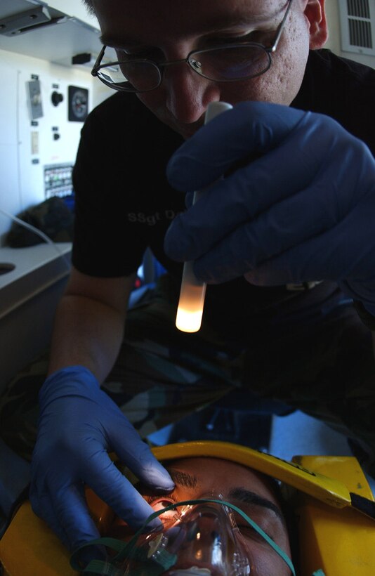 EIELSON AIR FORCE BASE, Alaska -- Staff Sgt. Robert Daly studies Senior Airman Derek Uburtis' eyes for discoloration, unequal pupils, foreign bodies or blood in the anterior chamber of the eye during a training exercise here.  They are assigned to the 354th Medical Group.  (U.S. Air Force photo by Airman 1st Class Anthony Nelson Jr.)