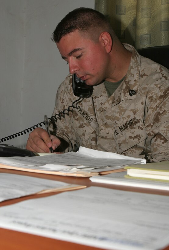 Sergeant Rolando A. Palacios, purchasing representative, supply section, II Marine Expeditionary Force, Headquarters Group, II MEF (FWD), takes a call in his office Aug. 10, 2005. Palacios works in Camp Fallujah supplying fellow Marines with the gear they need, and going above and beyond the call of duty.