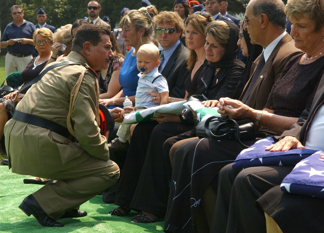 ARLINGTON NATIONAL CEMETERY, Va. -- Major Gen. Kamal Abdul-Sattar Barzanjy, Iraqi Air Force commander, presents the Iraq flag to Gen. and Mrs. Hussam Abass Ali, the parents of Capt. Ali Hussam Abass Alrubaeye, during a funeral held here Aug. 11 for the captain and four U.S. Airmen who died May 30 in an aircraft accident in Iraq. (U.S. Air Force photo by Staff Sgt. Amber K. Whittington)